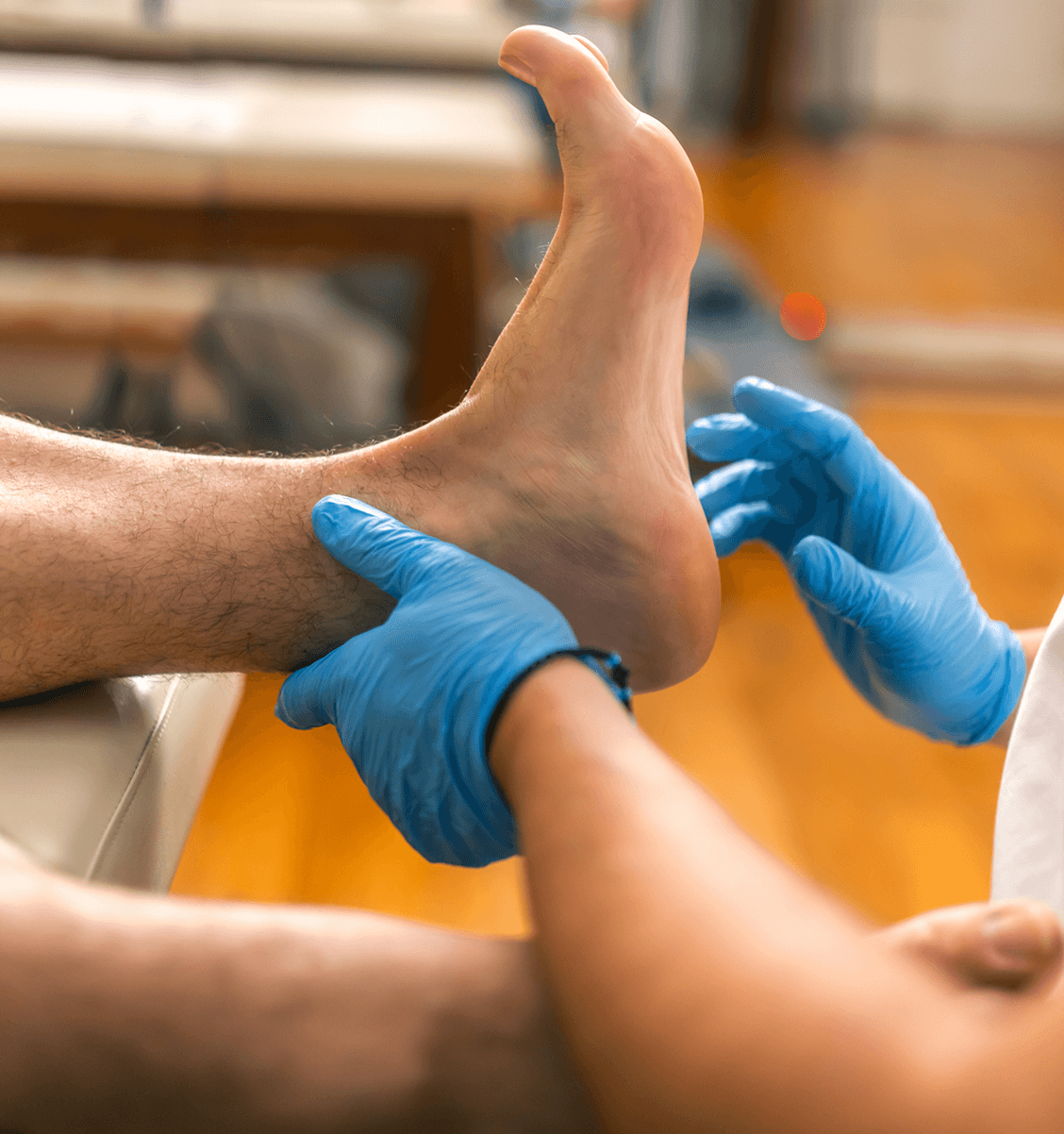 Foot examination by gloved hands on table.